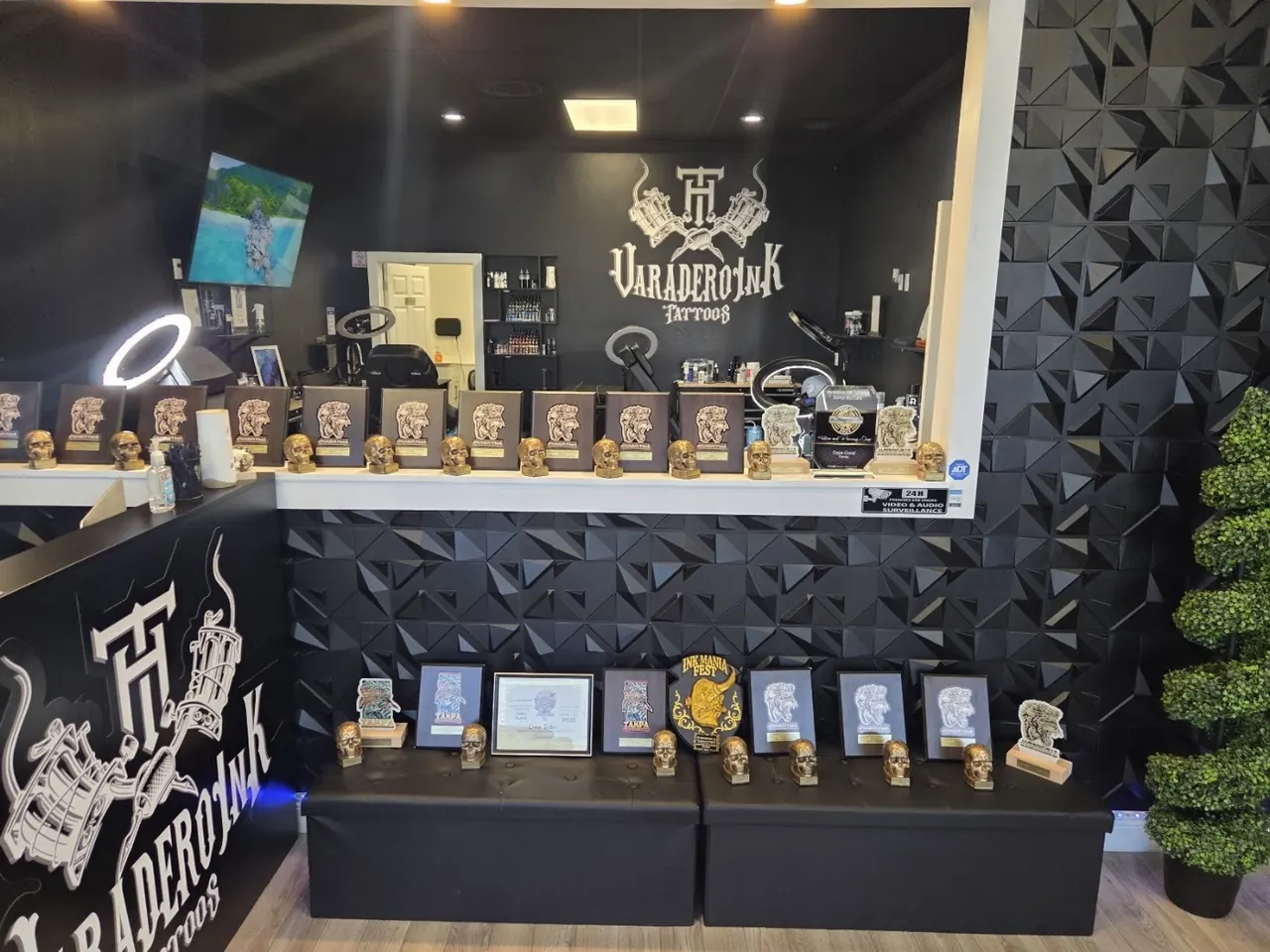 Varadero Ink lobby with a shelf of trophies and plaques, black faceted wall and the shop logo